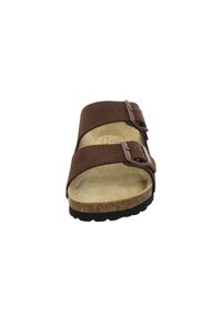 Brown slip-on sandal with two adjustable buckles, a contoured cork footbed, and a textured black rubber outsole. Simple and functional design.