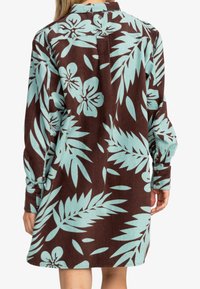 Robe chemise en velours côtelé brun et aqua avec de grands motifs floraux et de feuilles, des poignets boutonnés et une coupe décontractée avec un col.