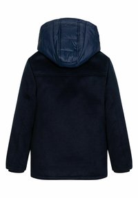 Navyblå kappa med en puffy huva, strukturerad tyg och långa ärmar. Har en rak skärning och en mjuk foder.