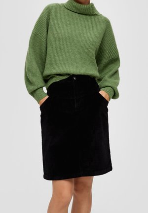 Un pull en tricot côtelé vert avec un col haut et des épaulettes tombantes, associé à une jupe en velours côtelé noire avec des poches latérales.