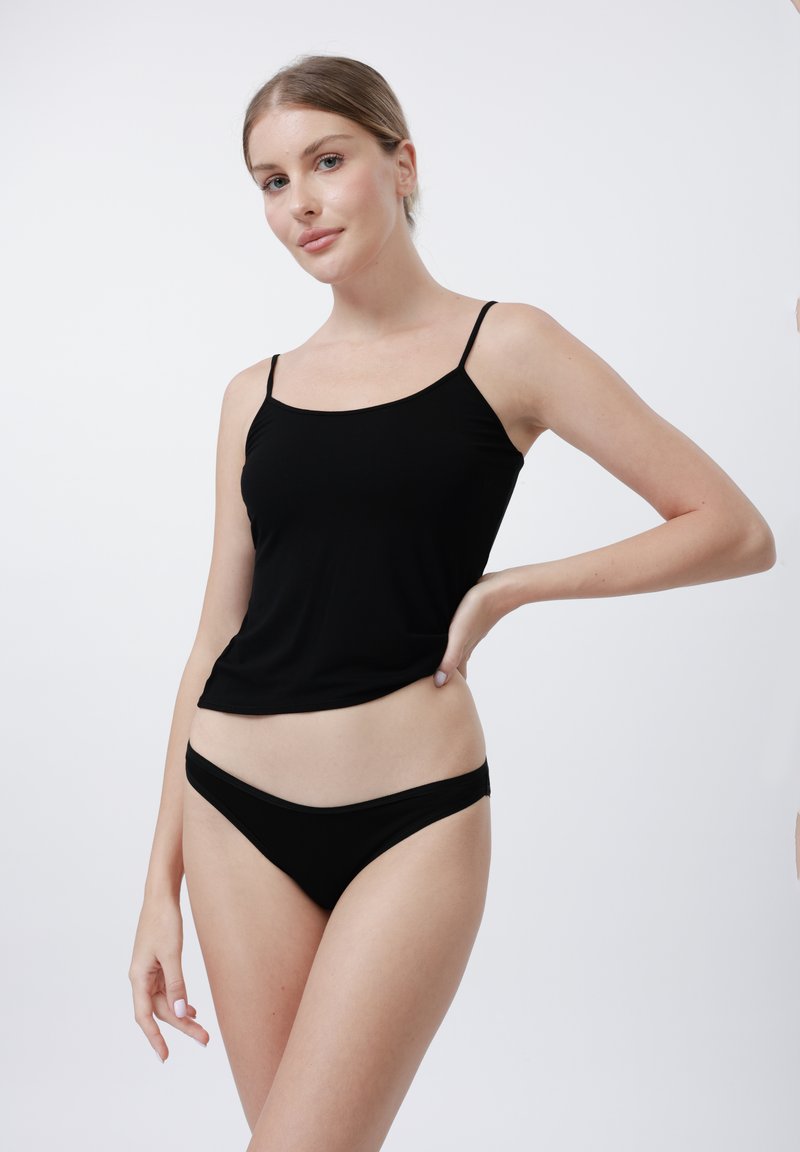 Svart cami med tynne stropper, med en glatt tekstur og tettsittende design, sammen med matchende svart bikiniunderdel.