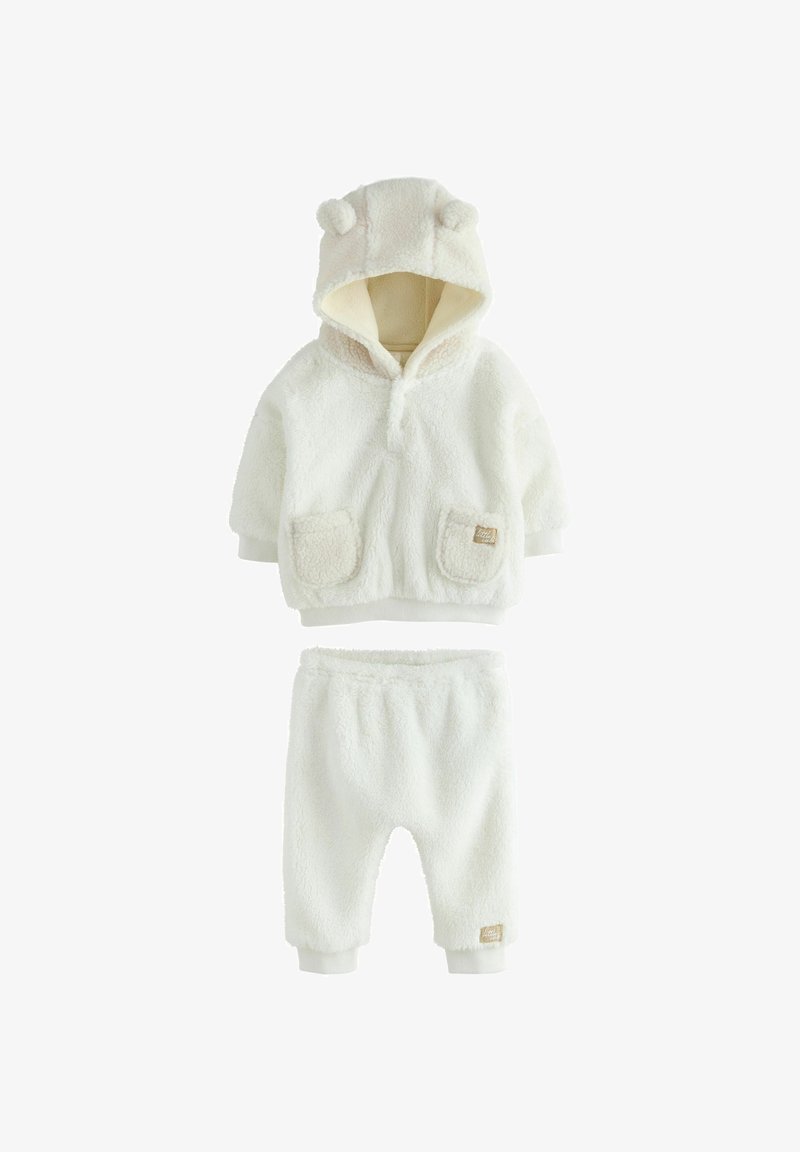 Ensemble en polaire deux pièces en blanc cassé, avec une capuche ornée d'oreilles d'ours, des poches décoratives sur le haut et une taille élastique sur le pantalon.