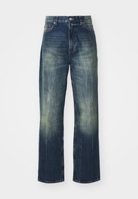 Vaqueros de mezclilla azul con lavado descolorido, piernas anchas y sutiles desgastes. Cuenta con una cintura clásica con botón y diseño de cinco bolsillos.