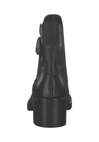 Bottine en cuir noir avec un talon épais, un panneau arrière texturé et un détail en métal sur le côté. Fini lisse avec un bout arrondi.