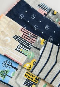 Färgglada strumpor i bomullsblandning med stadsbilder, snöflingor och ränder; nyanser inkluderar blå, marinblå, rosa och beige. Detaljerade mönster synliga.