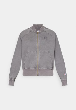 Graue Zip-Jacke mit gerippten Bündchen und Saum, ausgestattet mit zwei Fronttaschen und einem kleinen Logo auf der Brust. Strukturierte Stoff mit einem verblassten Finish.