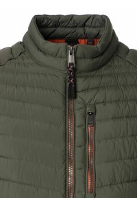 Grüne gesteppte Puffjacke mit hohem Kragen, Vorderreißverschluss und orangefarbener Futter. Verfügt über zwei mit Reißverschluss verschließbare Taschen und kontrastierende Beschläge.