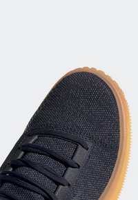 Sneaker in tessuto blu navy con tomaia testurizzata, caratterizzato da lacci neri e suola in gomma flessibile. Punta arrotondata con dettagli minimi.