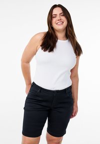 Shorts de mezclilla negros con un diseño ajustado, que cuentan con un cierre de botón y bolsillos laterales, combinados con una blusa sin mangas blanca.