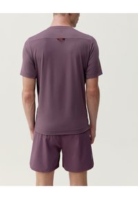 Kortærmet atletisk skjorte i mauve stof med detalje af slids på ryggen. Parret med matchende shorts, som alle har en glat, struktureret finish.