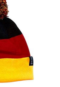 Strikket hue med sorte, røde og gule vandrette striber, toppet med en flerfarvet pompon og et lille sort mærke på det gule bånd.