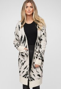 Sweter kardigan z beżową bazą i czarnym abstrakcyjnym wzorem, z otwartym przodem, bocznymi kieszeniami oraz ściągaczami przy mankietach i u dołu. Teksturowany, przytulny materiał.