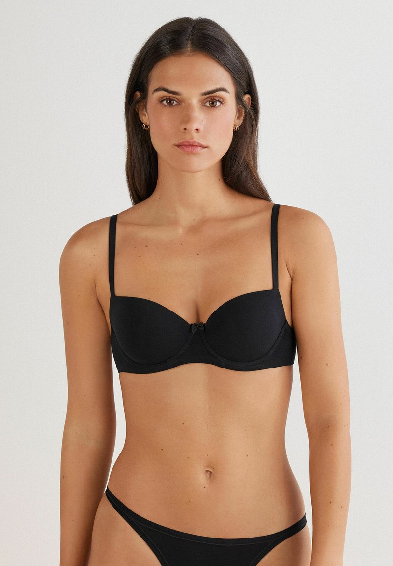 Sort underwire bh med formede skåle, justerbare stropper og en lille sløjfe detalje i midten. Glat stof med et sømløst design.