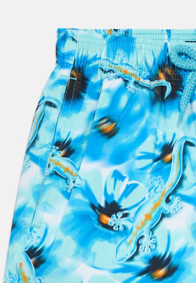 Úszónadrág élénk kék virágmintával, mely narancssárga és fekete részleteket tartalmaz, könnyű anyagból készült, gumis derékrésszel és húzózsinórral.