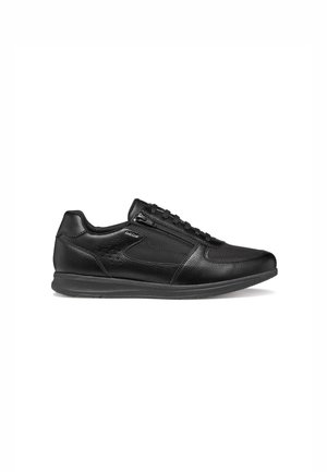 Sneaker in pelle nera low-top con zip laterale, lacci frontali e suola strutturata, posizionata con orientamento verso destra su sfondo bianco.
