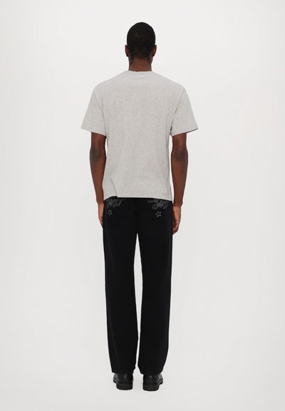 Gray cotton t-shirt paired with black wide-leg pants featuring embroidered accents. The outfit is completed with black shoes.