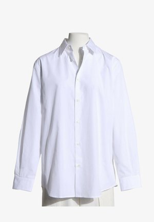 Camisa blanca de manga larga con botones y cuello, mostrada en un maniquí sin cabeza sobre un fondo blanco.