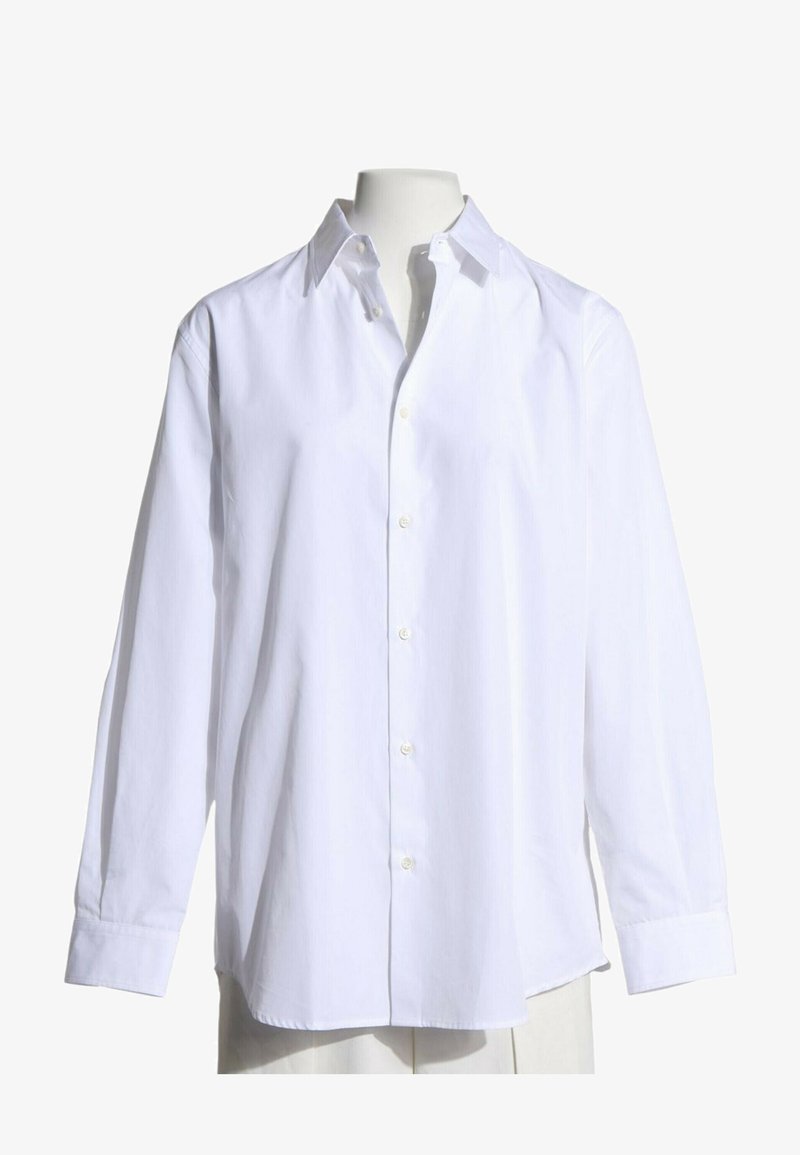 Chemise blanche à manches longues avec col, portée sur un mannequin sans tête sur fond blanc.
