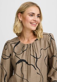 Brauner Pullover mit schwarzem abstrakten Linienmuster, gerafftem Ausschnitt und puffärmeligen langen Ärmeln aus leichtem Stoff.