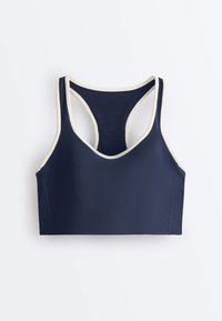 Brassière de sport bleu marine avec bordure blanche, design à dos nageur et larges bretelles, posée à plat sur un fond blanc.