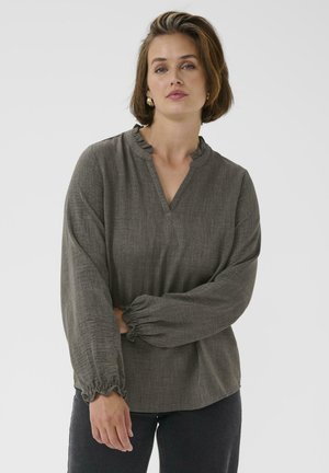 Blouse à manches longues, vert-grisâtre, avec un décolleté en V froncé et des poignets froncés. Tissu texturé avec une coupe ample.