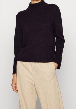 Mörklila polotröja med ribbad textur och långa ärmar, parat med ljusbeiga vida byxor.