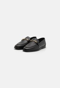Mocassins en cuir noir avec un accent en chaîne dorée. Texture lisse, design à bout rond et semelle plate offrent une apparence classique.