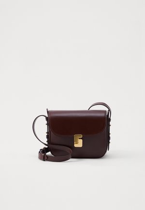 Brūna ādas plecu soma ar vāku, zelta aksesuāriem un sānu uzgaļiem. Aprīkota ar regulējamu siksnu un gludu tekstūru.