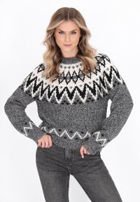 Grauer Strickpullover mit schwarz-weißen geometrischen Mustern, runden Halsausschnitt und gerippten Bündchen und Saum. Das strukturierte Garn verleiht Tiefe.