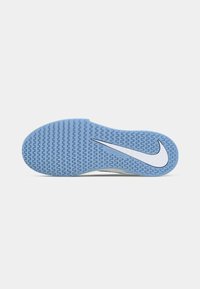 Outsole αθλητικού παπουτσιού Nike, με υφή από μπλε καουτσούκ και λευκό σχέδιο λογότυπου, καθώς και στρογγυλεμένη φτέρνα για σταθερότητα.
