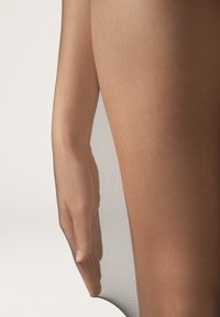 Przezroczyste, brązowe rajstopy prezentowane na tle ręki. Materiał jest lekki i gładki, z delikatną teksturą i minimalnym połyskiem.