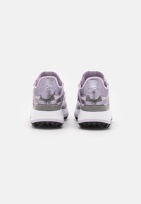 Purple running shoes with a metallic silver accent. Features a textured sole and cushioned heel, showcasing minimalistic design elements.