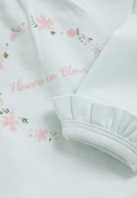 Hellblaues Sweatshirt mit floralem Druck in Pink und Grün, mit dem Text "Flowers in Bloom" und einem Rüschensaum.