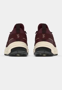 Μπορντό αθλητικά παπούτσια με επάνω μέρος από πλέγμα, αντίθετη κρεμ σόλα και μαύρη επιφάνεια τριβής. Διαθέτουν λαβή για εύκολη φόρεση και ανθεκτική κατασκευή.