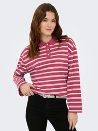 Polo à manches longues rayé rose et blanc avec col et patte de boutonnage à trois boutons, porté avec un jean noir taille haute et une ceinture argentée.