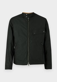 Jachetă neagră cu guler ridicat, închidere frontală cu fermoar și buzunare laterale. Are un buzunar cu clapetă și închidere cu capse pe piept.