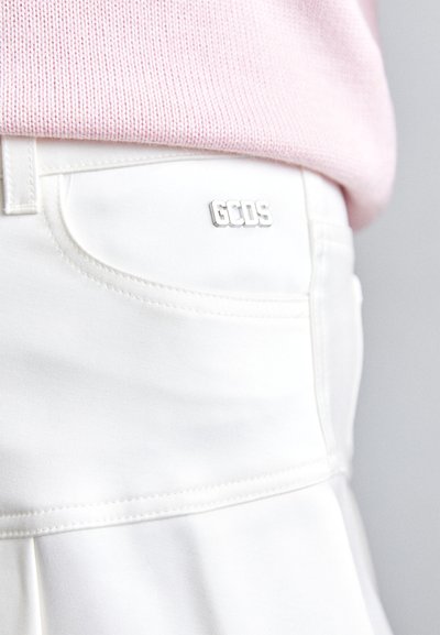 White fabric shorts with a smooth texture and reinforced stitching. Features a silver GCDS logo on the waistband.