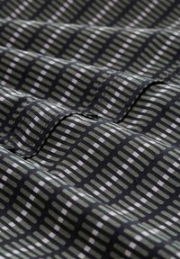 Fabric with a dark background and a grid pattern in shades of green and white. Textured surface with alternating rectangular shapes.