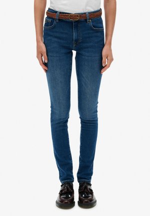 Blauwe skinny jeans van denim met een hoge taille, met vijf zakken, een bruine gevlochten riem en donkere schoenen met kwastjes.