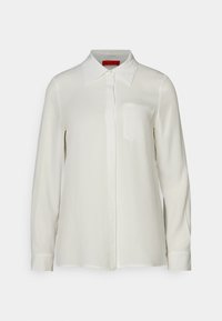 Hvid langærmet bluse med krave og frontlomme. Lavet af glat stof og har en knaplukning foran samt manchetter på ærmerne.