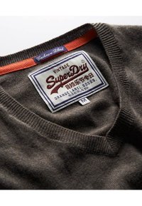 Brauner Cashmere-Mix-Pullover mit V-Ausschnitt. Verfügt über einen orangefarbenen Akzent am Kragen und ein Etikett mit "Vintage SuperDry"-Markierung.