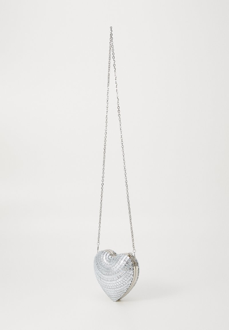 Srebrna torebka w kształcie serca z teksturowaną, lustrzaną powierzchnią, z metalowym łańcuszkiem i eleganckim zapięciem.