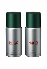 Två cylindriska deodorantsprayburkar med silverfärgad kropp, gröna lock och röd text som säger "HUGO" och "MAN." Varje burk rymmer 150 ml.
