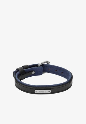 Bracelet Fossil réglable en cuir noir et tissu bleu marine avec boucle en métal et plaque logo, présenté dénoué sur fond blanc.