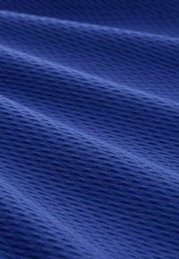 Tkany materiał w głębokim odcieniu niebieskiego z wypukłymi, falistymi wzorami tworzącymi fale. Materiał wydaje się miękki, o jednolitym splocie i delikatnym połysku.