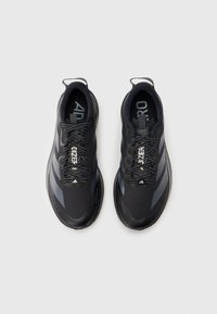 Chaussures de sport noires avec tiges en mesh, accents sombres contrastants et semelles en caoutchouc. Elles comportent des lacets et un logo sur la languette.