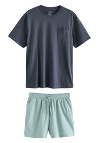 T-shirt pour homme à manches courtes en coton bleu marine avec une poche poitrine, associé à un short de détente vert clair texturé avec une taille élastique.