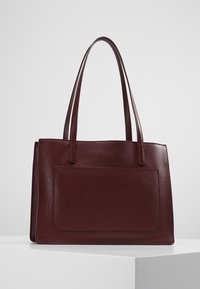 Bordowa skórzana torebka z dwiema długimi rączkami, gładkim wierzchem i przednią kieszonką. Teksturowana powierzchnia i prostokątny kształt.