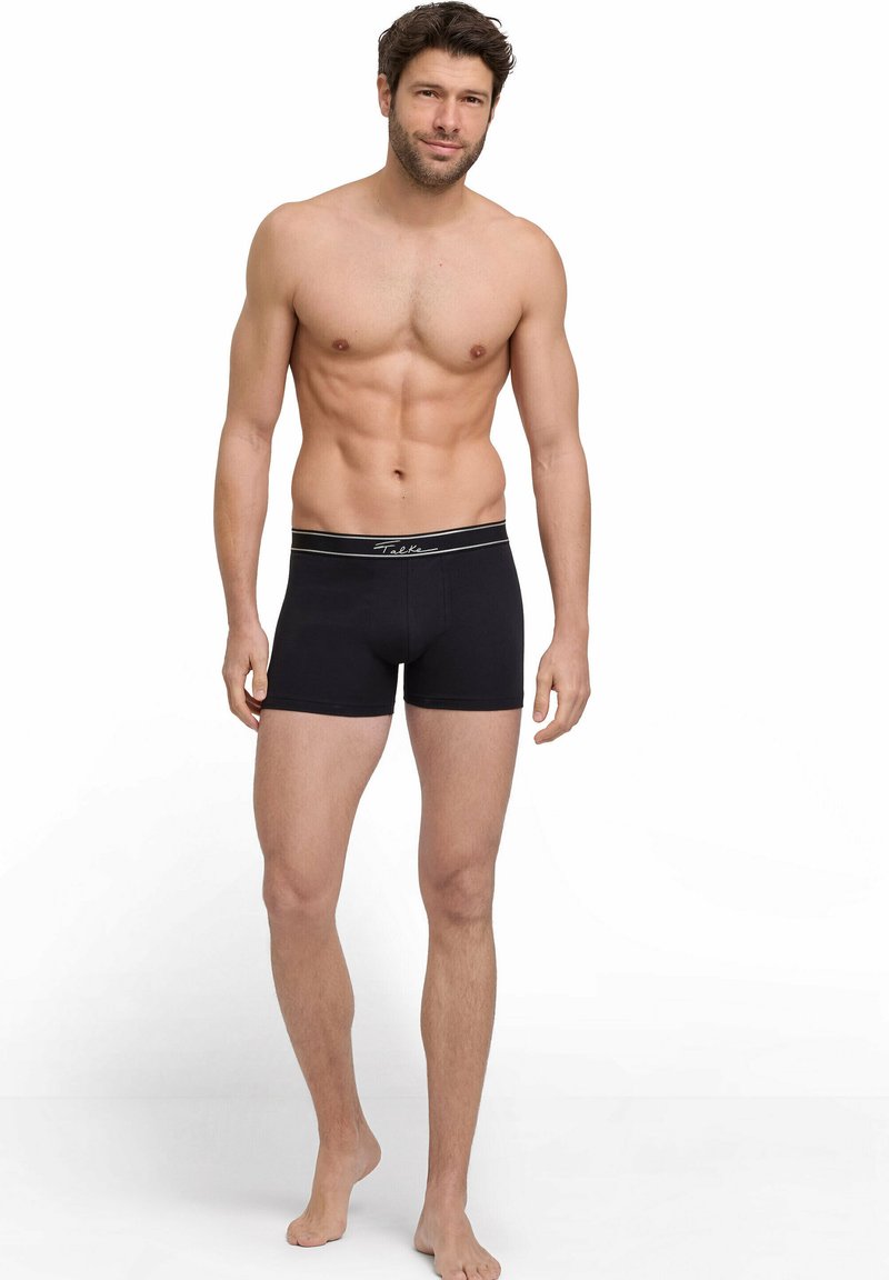 Black boxer briefs with a branded waistband, featuring a snug fit and smooth fabric texture, worn by a male model against a plain background.