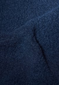 Navy blue textured fabric with a soft, fuzzy surface and slight shimmer, exhibiting a smooth, flowing shape and varied depth.